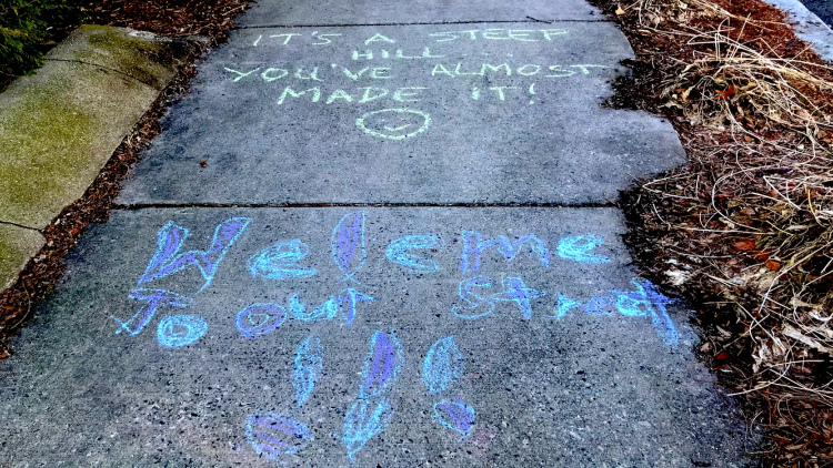 sidewalk chalk message saying "welcome to our street"