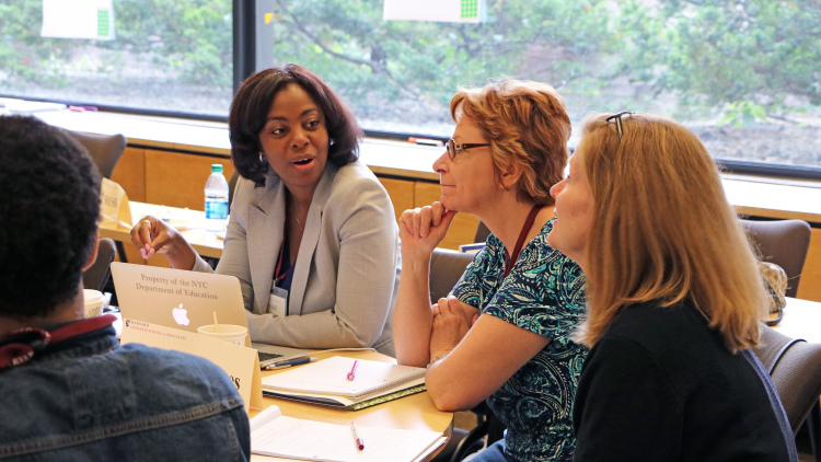 Three Data Wise participants converse at a table at HGSE